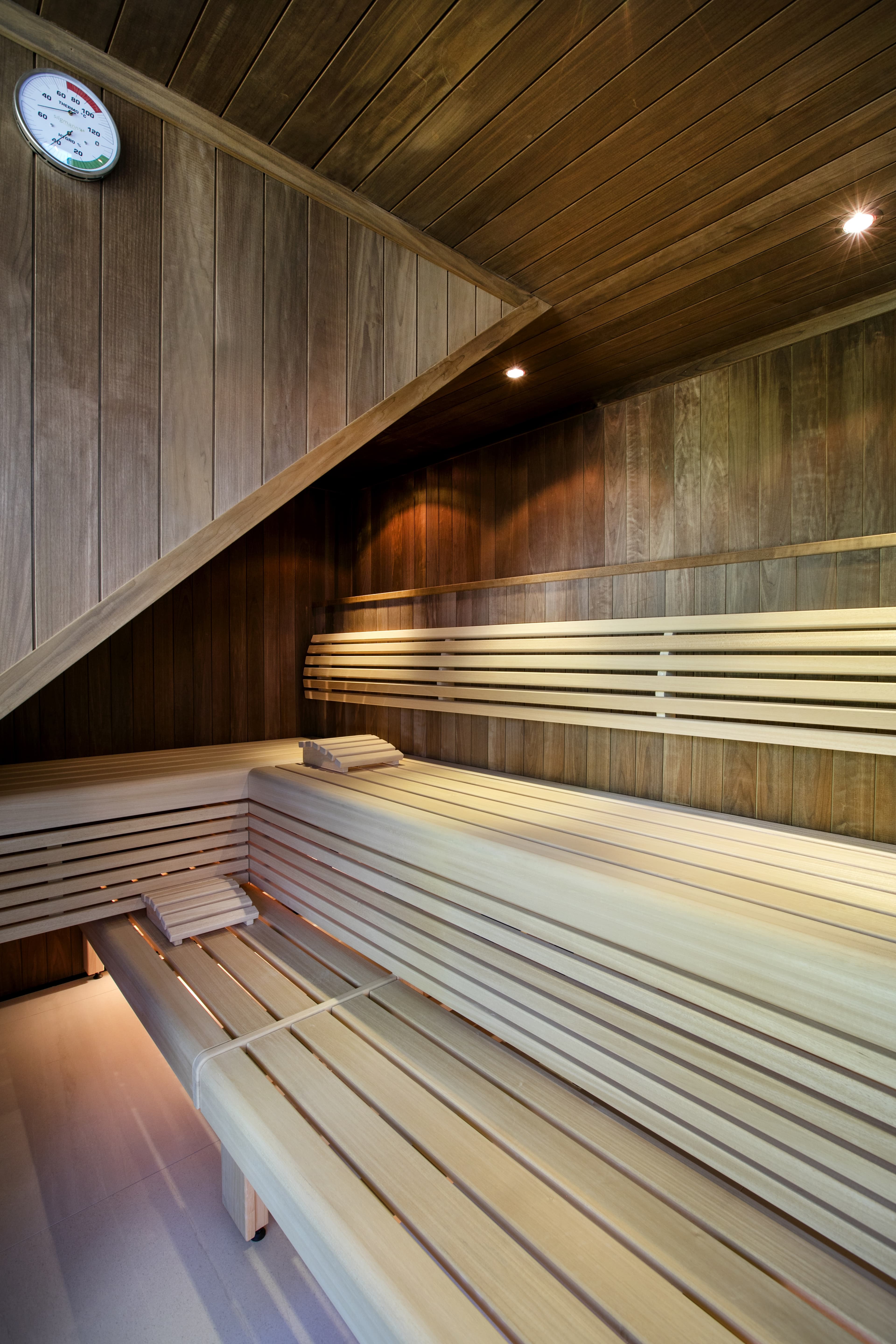 Modern sauna in Hotel Spitzerberg with wooden benches and a temperature gauge on the wall.